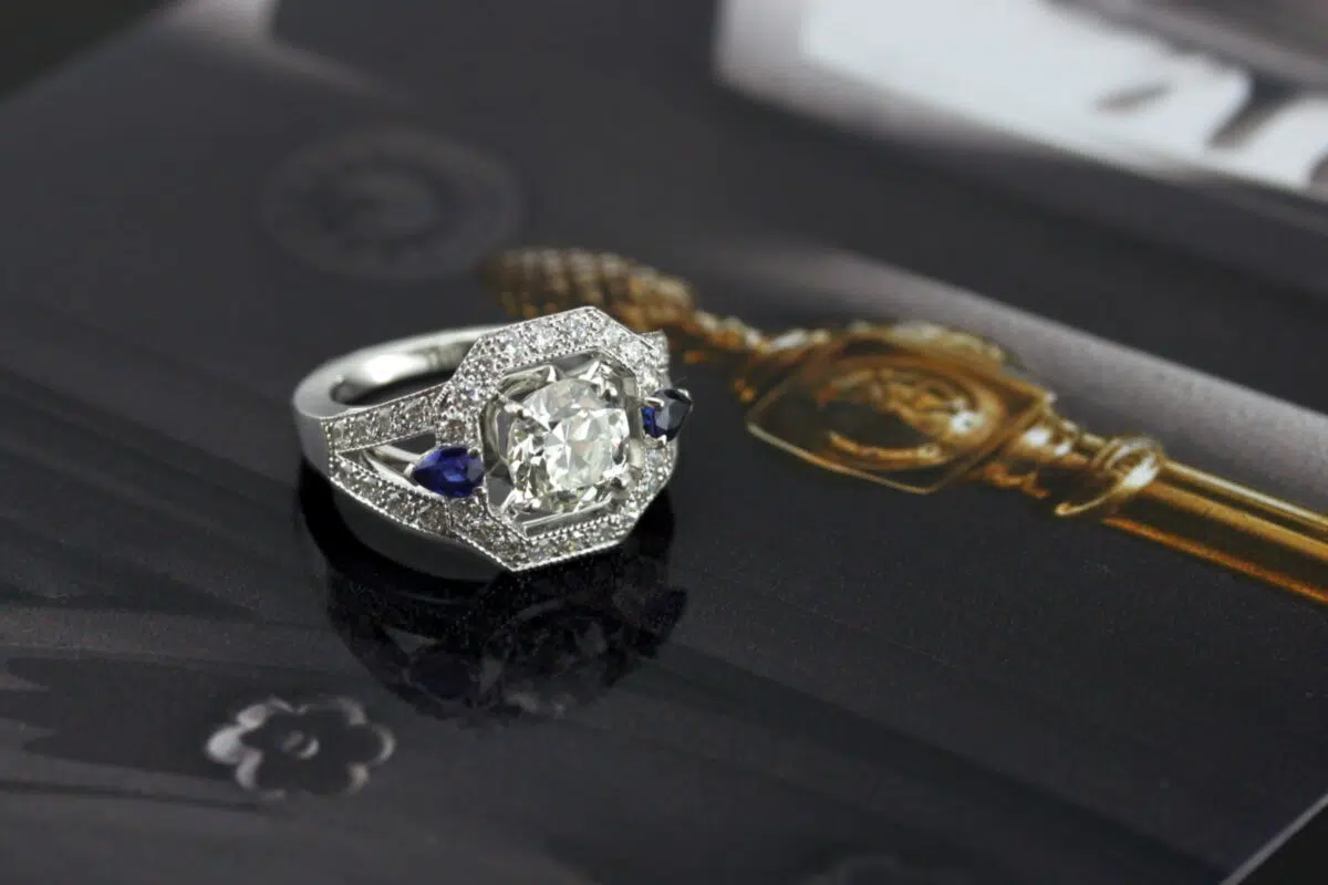 piece unique bague en or blanc 18 carats pavée de diamants avec deux saphirs bleus entourant un diamant central