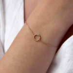 Bracelet en or rose 18 carats en forme d'anneau torsadé avec un diamant en or rose et une pierre grenat vert, porté sur le poignet d'un modèle