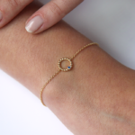 Bracelet en or rose 18 carats en forme d'anneau perlé avec un diamant en or rose et une pierre saphir bleu, porté sur le poignet d'un modèle