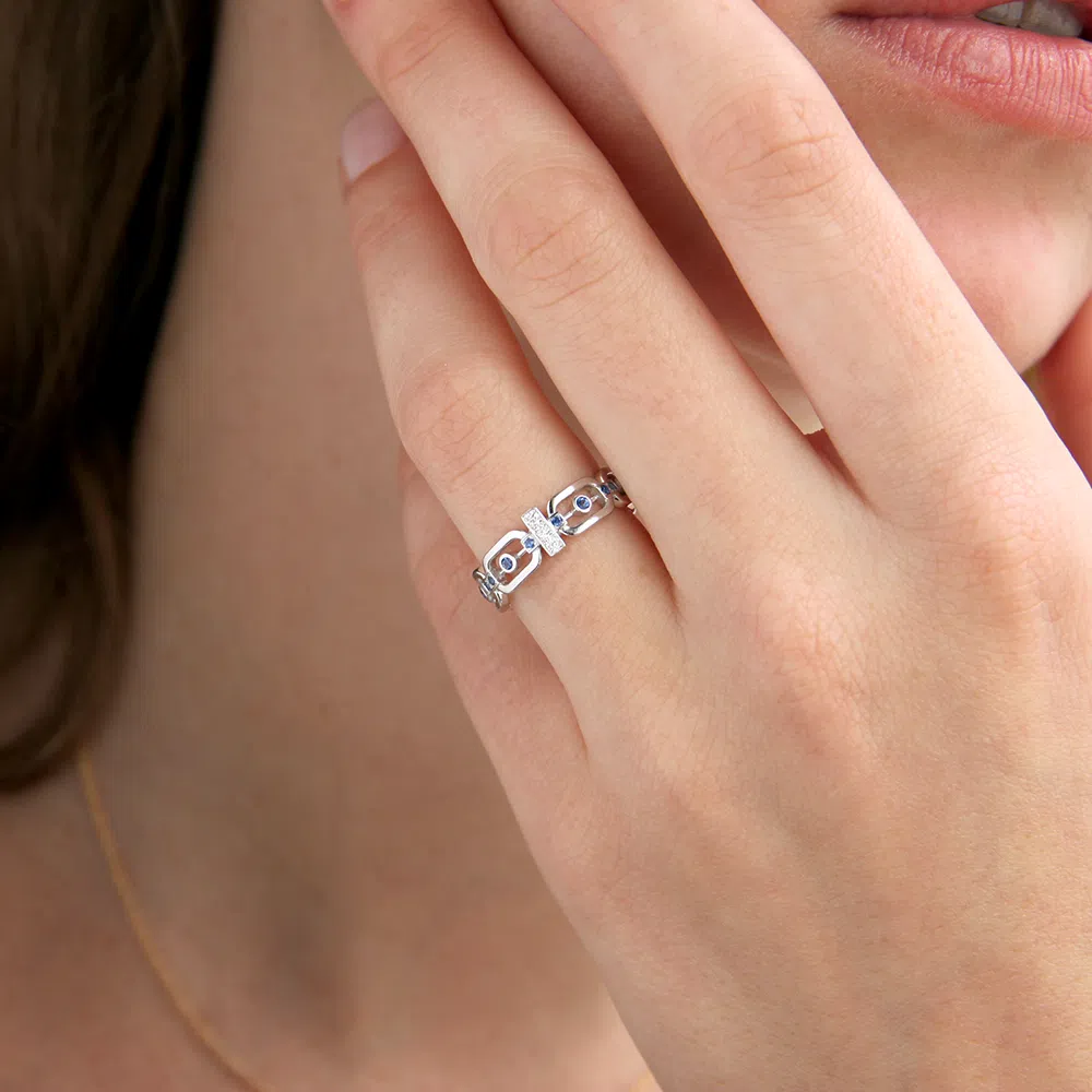 bague maillon en or blanc 18 carats avec des saphirs bleus ainsi qu'une barrette en or blanc et des diamants, portée sur un modèle doigt
