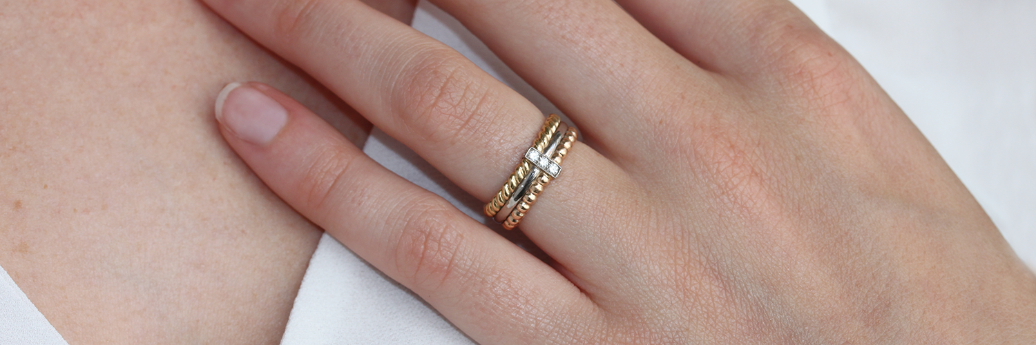bague multiple avec des anneaux en or 18 carats et une barrette en or blanc avec des diamants, portée sur un modèle doigt