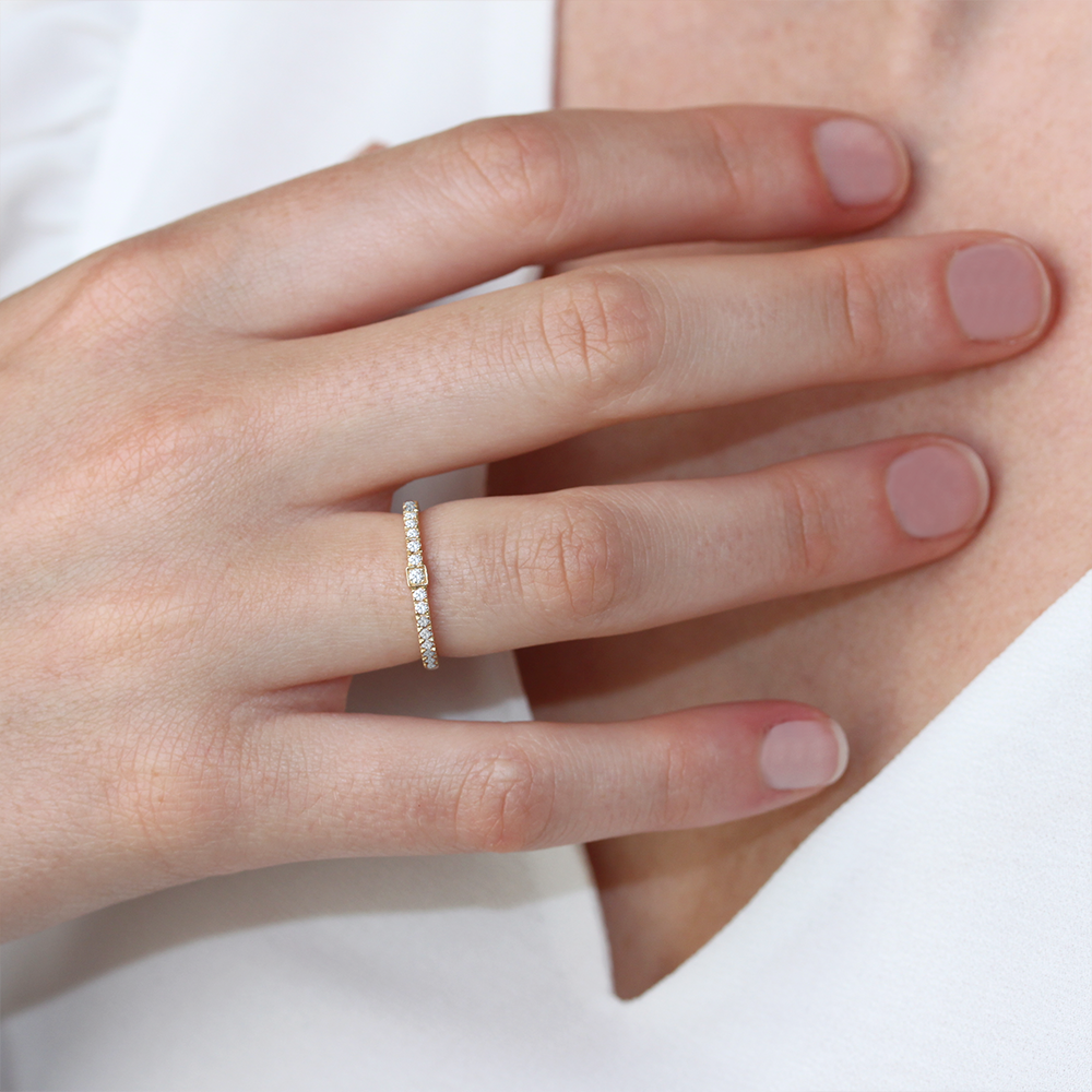 alliance en anneau serti en or blanc 18 carats avec un pavage et une barrette en or 18 carats, portée sur modèle doigt