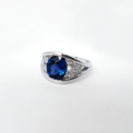 Bague en or blanc 18 carats composée de deux anneaux en forme de v comprenant un saphir bleu au centre de ces anneaux et de trois diamants autour de ce saphir bleu