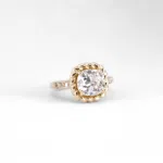 Bague solitaire en or jaune 18 carats serti un d'un diamant en pierre de centre entouré d'une torsade et de diamants sur la moitié de l'anneau.