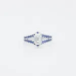 Bague en or blanc 18 carats sertie de saphirs bleus sur les anneaux en V, sublimé par un diamant en pierre de centre.