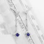 Paire de boucle d'oreille pendante en or blanc 18 carats sertie sur toute la longueur de diamants, puis d'un saphir bleu en bas de chacune d'elles.