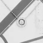 Pendentif en or blanc 18 carats serti d'un diamant entouré de diamants, ainsi qu'une chaîne en or blanc 18 carats.