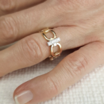 Bague maillon en or jaune 18 carats avec une barrette en or jaune 18 carats sertie de diamants porté sur le doigt d'une main.